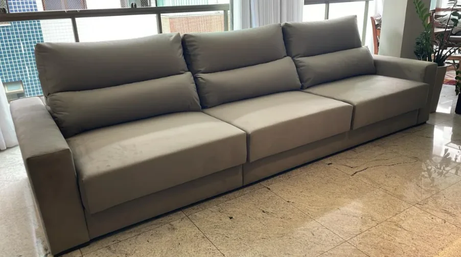 Sofá grande cinza com três lugares e encostos acolchoados